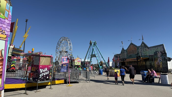Des familles se promènent dans la zone des manèges de la Western Fair.
