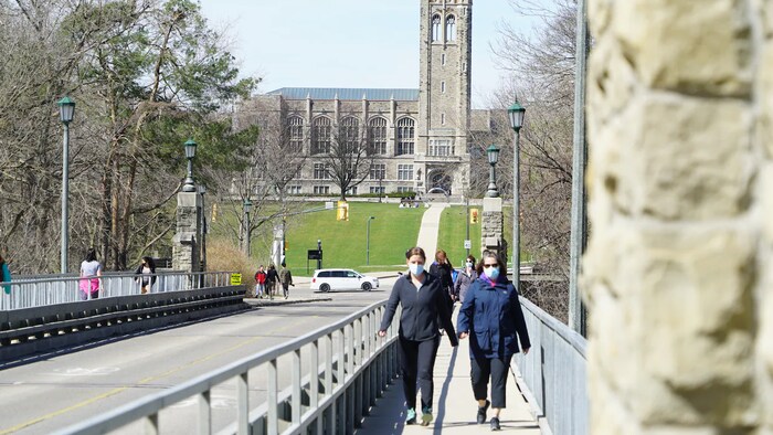 Des femmes traversent un viaduc devant l'Université Western.
