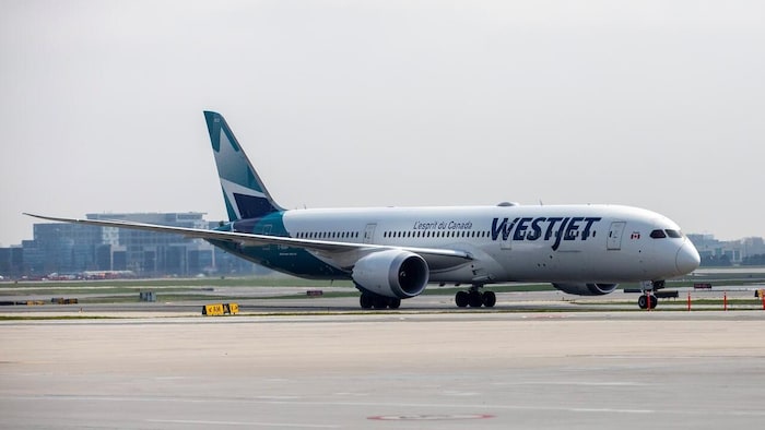 Un avion de WestJet sur une piste d'aéroport.