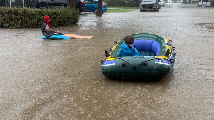 Un enfant et une femme qui flottent dans une rue inondée.