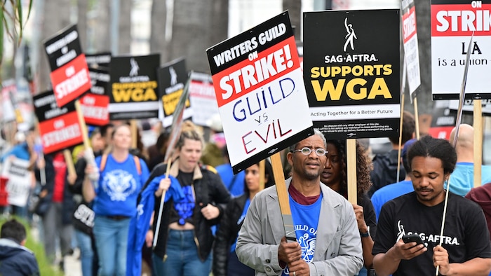 Des personnes tiennent des pancartes lors d'une marche en soutien au mouvement de grève de la WGA.