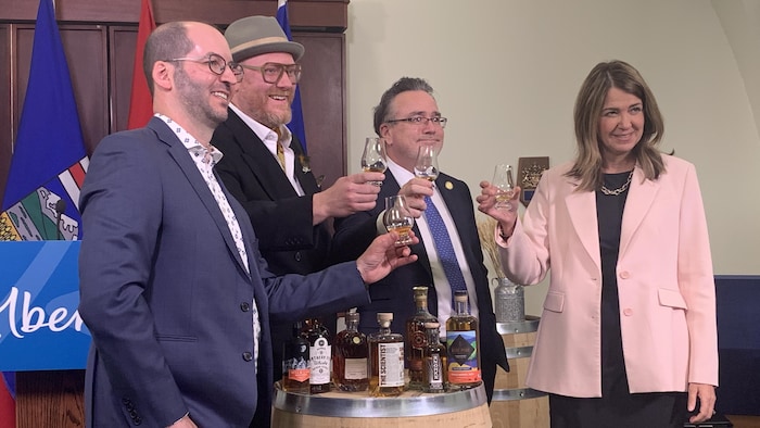 Quatre personnes, dont le ministre de Services Alberta et de la Réduction de la bureaucratie, Dale Nally, et la première ministre albertaine, Danielle Smith, boivent du whisky lors d'une conférence de presse.