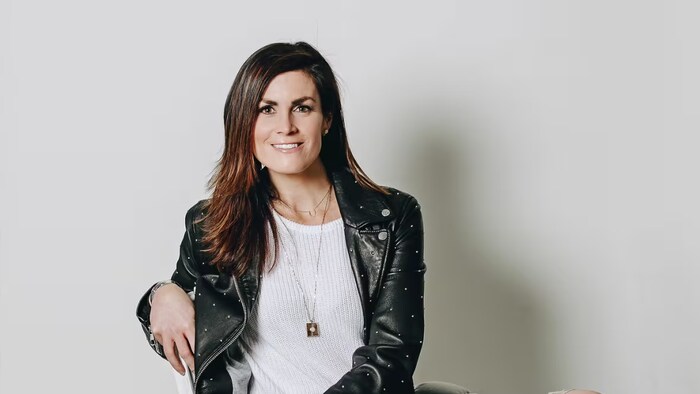 Une femme est assise sur une chaise tandis que, devant elle, se tient un chien.