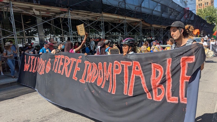 Des manifestants tiennent une banderole sur laquelle est écrit « Wild Pride – Fierté Indomptable ».