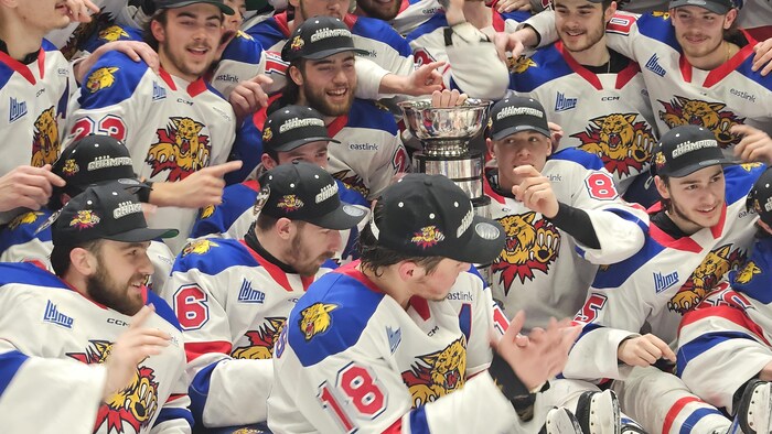 Des hockeyeurs rassemblés autour du trophée Gilles-Courteau