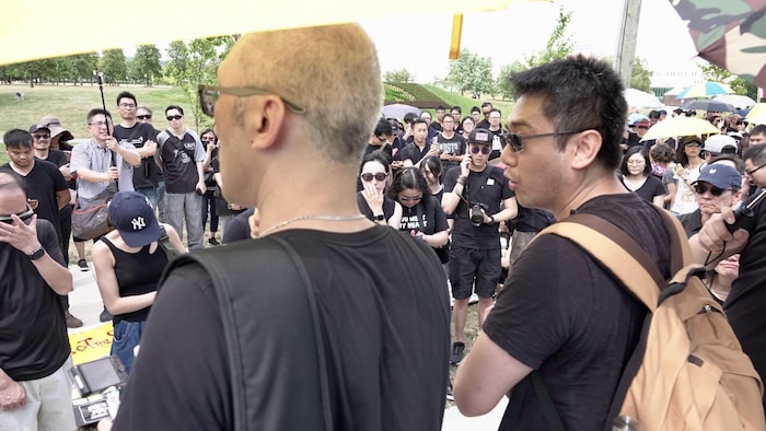 Deux manifestants de dos devant d'autres manifestants vêtus de noir.