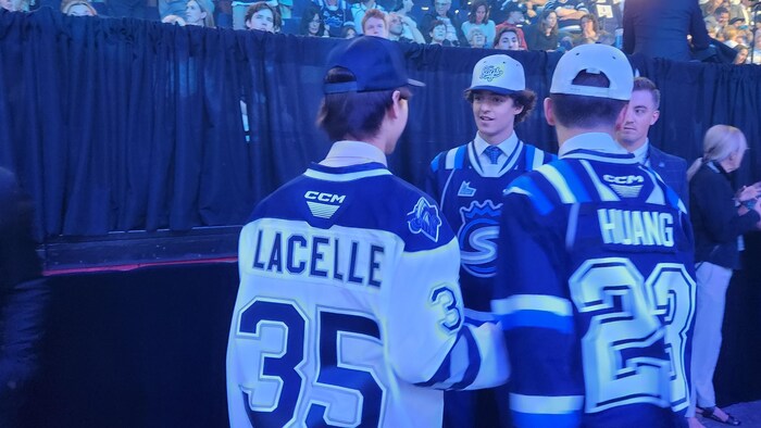 Un jeune joueur parle avec d'autres joueurs de hockey.