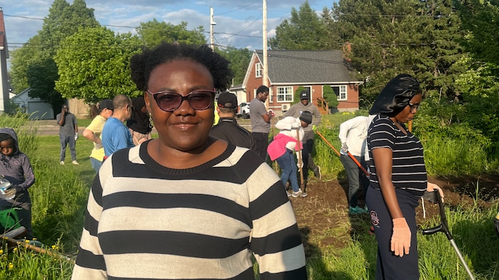 Williamide Deuko standing in front of the community garden.