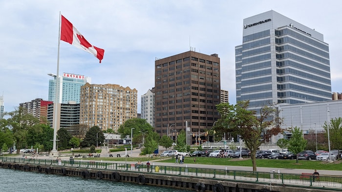 Des gratte-ciel vus de la rivière avec un grand drapeau du Canada.