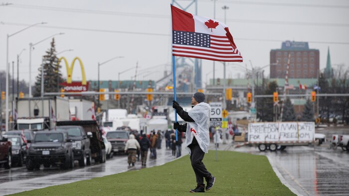 Un manifestant brandit un drapeau sur une voie d'accès au pont Ambassador.