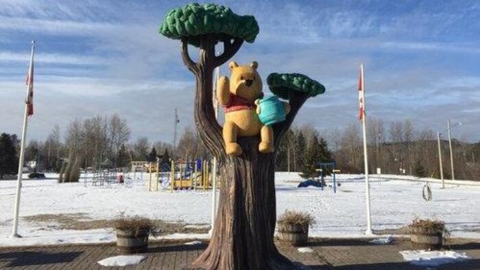Winnie est perché dans un arbre avec un pot de miel.