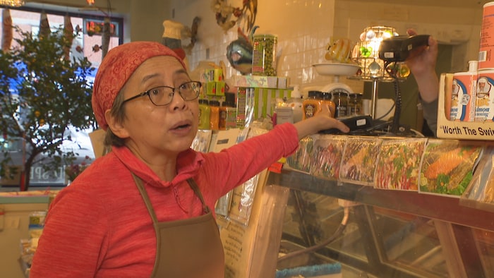 Winnie Shao dans son magasin et avec son terminal de paiement.