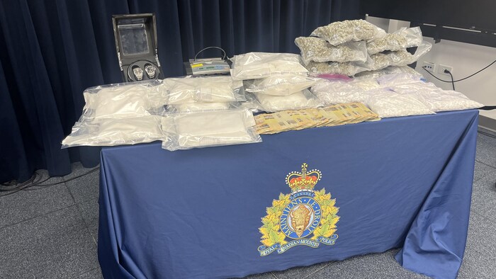 Une table sur laquelle est exposée une saisie de drogue et d'argent.