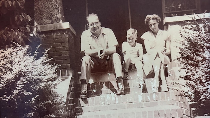 Deux adultes, un homme et une femme, assis sur un escalier avec un enfant au milieu.