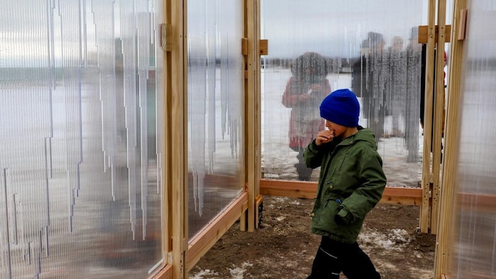 Un jeune garçon se promenant à travers l’installation « Glaciate », une série de panneaux verticaux en polycarbonate, remplis d’eau du lac voisin, le lac Ontario, crée un ensemble de lentilles de glace qui glacent la plateforme, à Toronto le 16 février 2026.