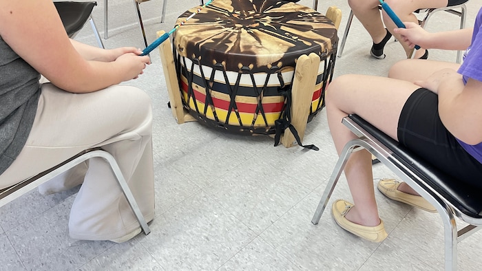 De jeunes filles sont assises autour d'un tambour.