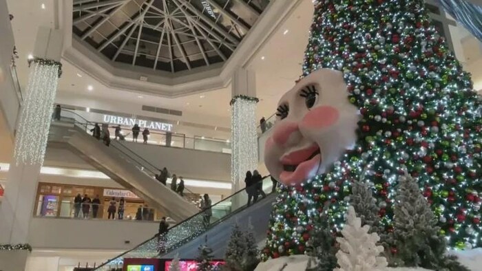 Un arbre décoré de boules de Noël avec un visage souriant au milieu.