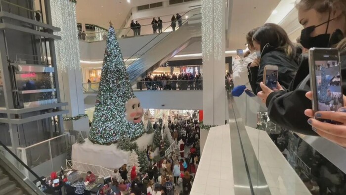 Un arbre de Noël avec un visage au milieu, entouré de centaines de personnes.