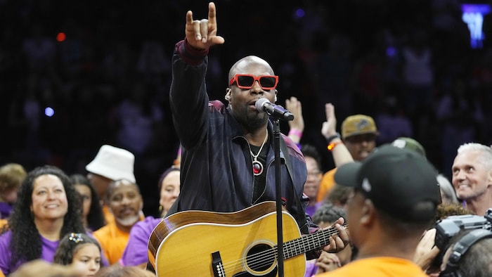 Une homme chante au milieu d'une foule.