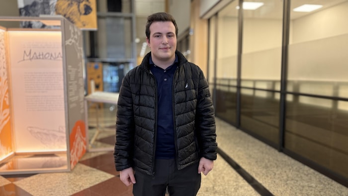 Un homme est debout et sourit à la caméra.
