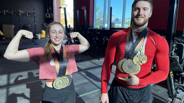 Les deux haltérophiles posent pour la caméra avec leurs médailles au cou.