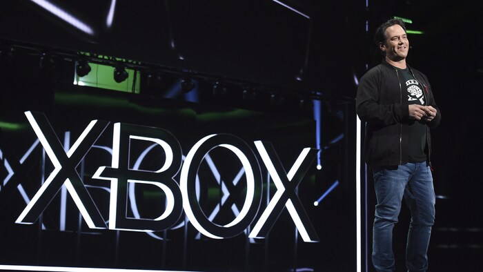 Phil Spencer sur une scène devant le logo de Xbox.