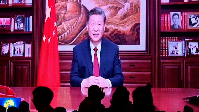 Des personnes dînent dans un restaurant alors qu'un écran retransmet le discours du président chinois Xi Jinping à l'occasion du Nouvel An, à Pékin, le 31 décembre 2023.