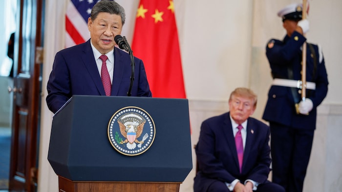 Xi Jinping prononce un discours à un pupitre, sous le regard de Donald Trump, assis en arrière-plan.