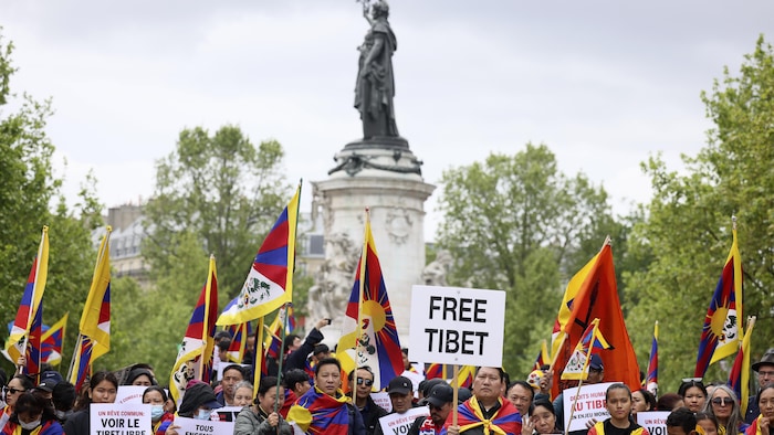 Des gens tiennent des drapeaux du Tibet lors d'un rassemblement. 
