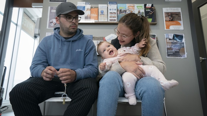 Un couple dans une salle d'attente avec leur bébé.