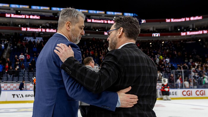 Deux hommes en veston se font l'accolade sur la patinoire.