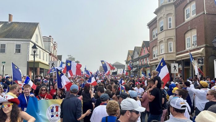 Des milliers de personnes portant des drapeaux acadiens.