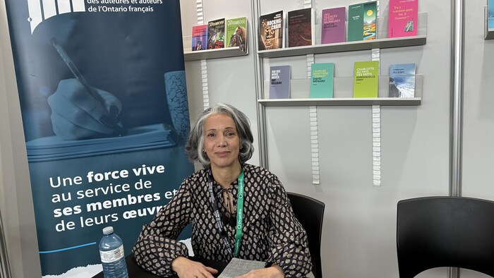 Yasmina Boubezari, la directrice générale de l’Association des auteures et auteurs de l’Ontario français, assise sur une chaise.