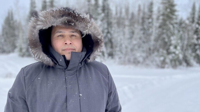 Wayne Neegan devant des arbres enneigés.