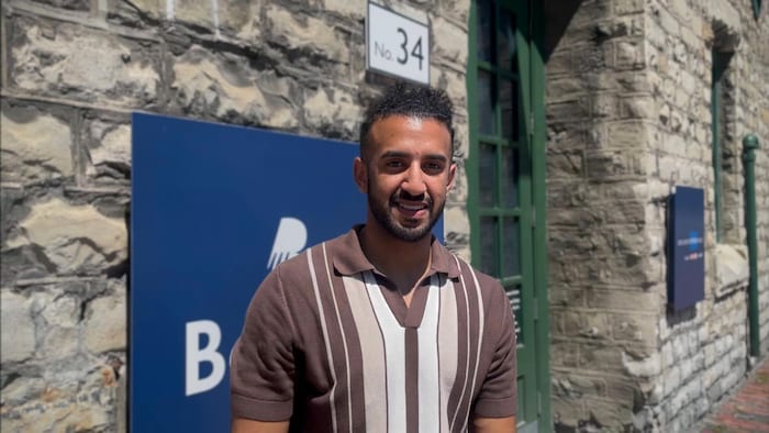 Un homme devant l'enseigne du Collège Boréal à Toronto