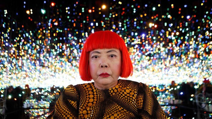 Portrait de l'artiste, dans une de ses salles de miroirs où l'on voit de nombreux objets lumineux.