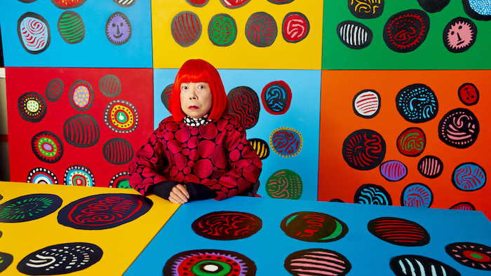 Yayoi Kusama entouré de ses peintures colorées.