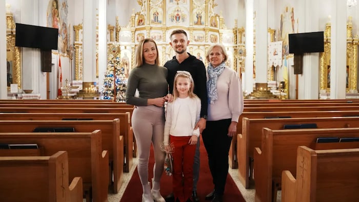 Vitali Hrechka poses for a photo with his wife Evelina, daughter Emiliia, and mother Hanna, after the St. Nicholas Day celebration at St. Demetrius Ukrainian Orthodox Church in Toronto on Sunday, Dec. 18, 2022. The family recently arrived in Canada after leaving their home in Ukraine’s Transkarpathia region. (Chris Young/The Canadian Press)