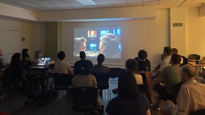 Un groupe de personnes assises dans une salle sombre pour regarder un film. 