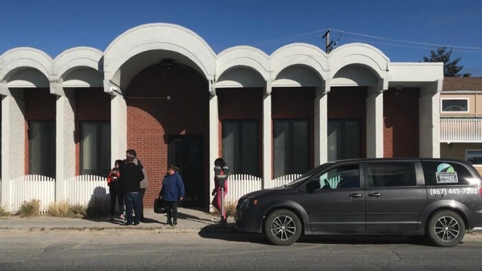 Un groupe de personnes attendent devant l'établissement.