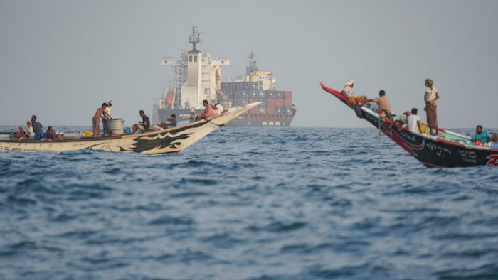 Des gens naviguent à proximité de navires ancrés. 
