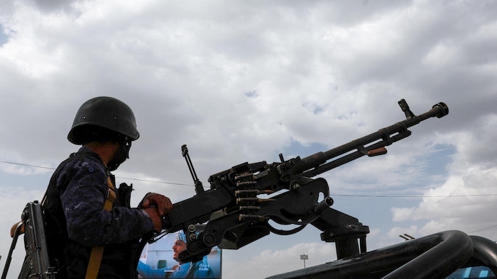Un membre des forces de sécurité houthistes tient une mitrailleuse montée à l'arrière d'un véhicule de patrouille sur le lieu d'un rassemblement anti-saoudien.