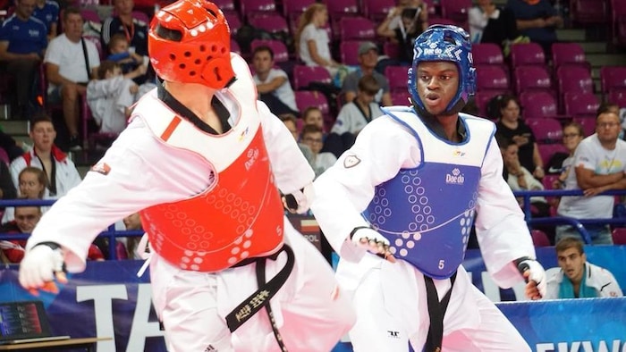 Il se bat contre un adversaire dans une compétition de teakwondo. 