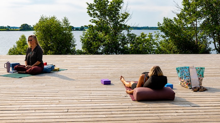 Deux personnes font du yoga au bord de la rivière Winnipeg.