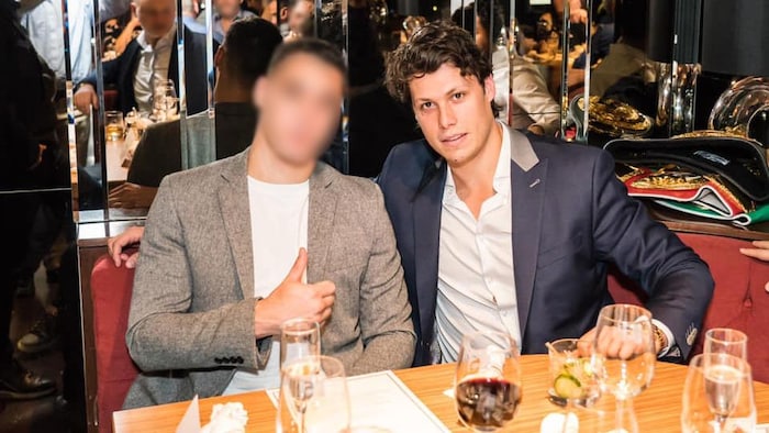 Un jeune homme avec un veston assis à la table d'un chic restaurant.