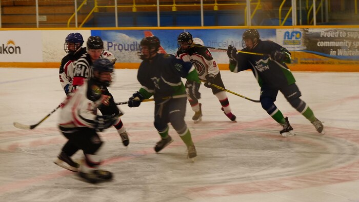 Des joueurs se disputent la rondelle sur la glace autour d'un arbitre.