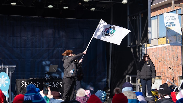John Rodda brandit le drapeau des Jeux d'hiver de l'Arctique.