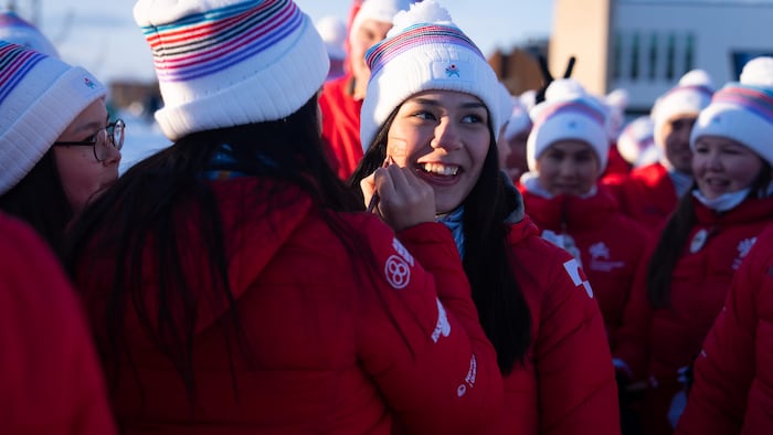 Une athlète peint un drapeau du Groenland sur la joue d'une coéquipière lors des Jeux d'hiver de l'Arctique 2026.