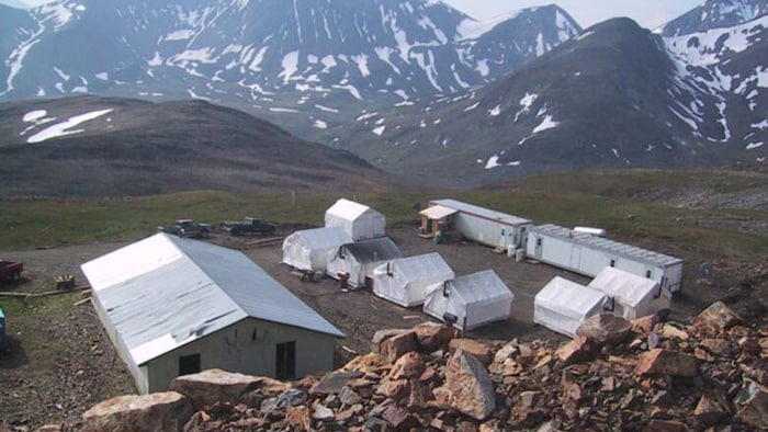 Quelques tentes et des roulottes au milieu des montagnes au camp de la mine Mactung.