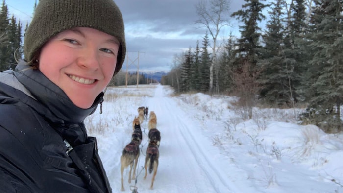Égoportrait de Louve derrière son attelage de chiens sur la piste.